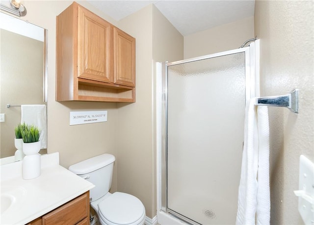 bathroom featuring vanity, a shower stall, and toilet