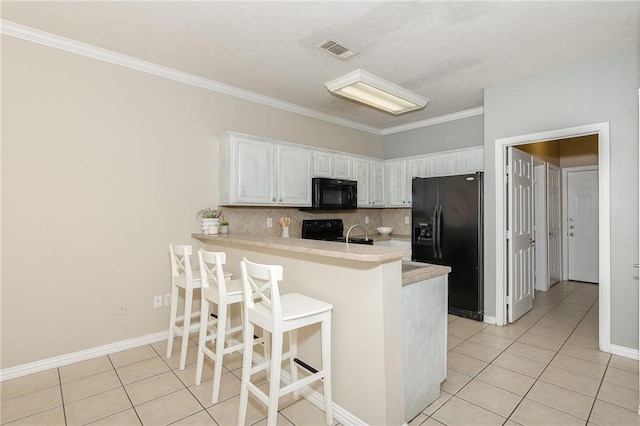 kitchen featuring black appliances, decorative backsplash, light tile patterned flooring, light countertops, and a peninsula