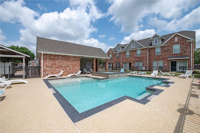 pool featuring fence, a hot tub, and a patio