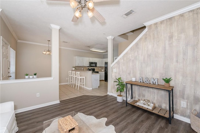 living room featuring visible vents, light wood-style floors, ornate columns, ceiling fan, and ornamental molding