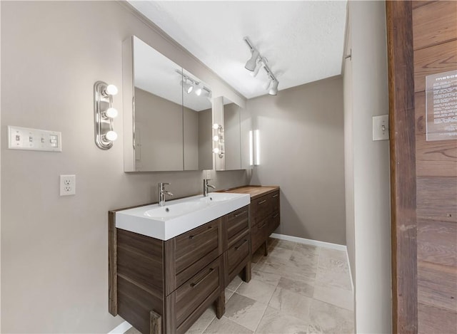 full bath with double vanity, baseboards, marble finish floor, and a sink