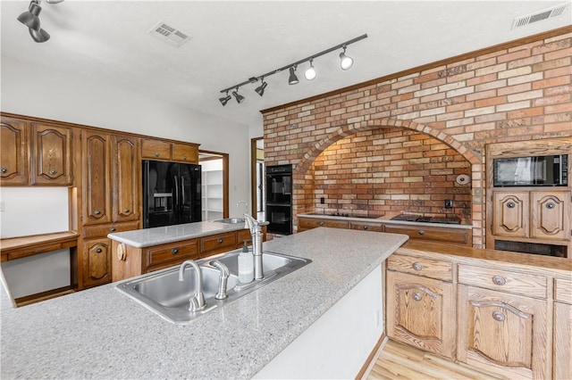 kitchen featuring black appliances, visible vents, brick wall, and a sink