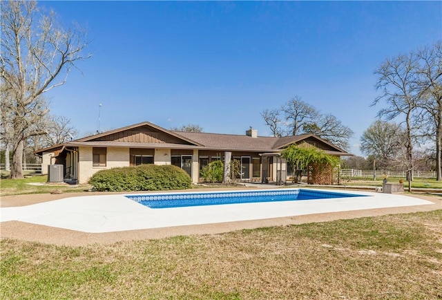 outdoor pool with central AC unit, a yard, and fence