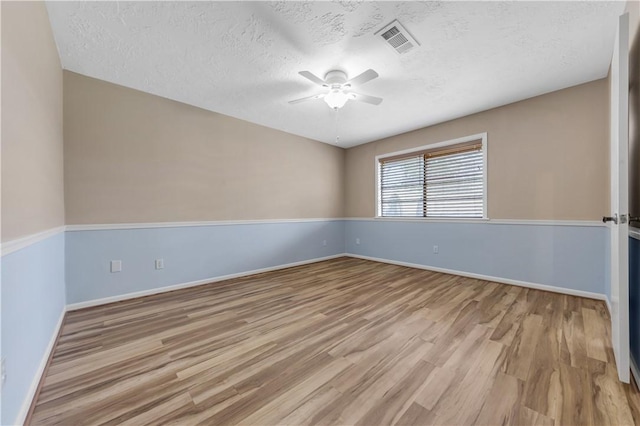 empty room with visible vents, baseboards, ceiling fan, wood finished floors, and a textured ceiling