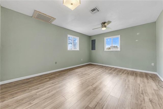 spare room with visible vents, baseboards, electric panel, wood finished floors, and a ceiling fan