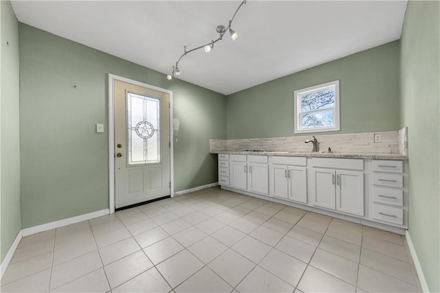 kitchen featuring a sink, baseboards, plenty of natural light, and white cabinets