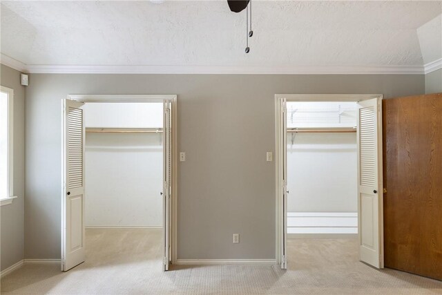 2629 Benton Dr, Brenham, TX 77833 - unfurnished bedroom featuring light carpet, ornamental molding, two closets, a textured ceiling, and a ceiling fan