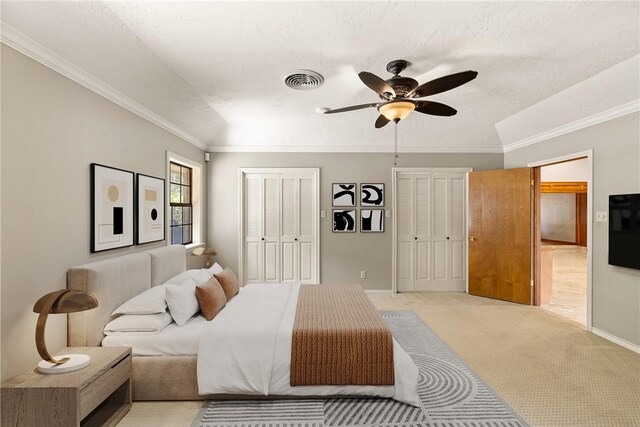 2629 Benton Dr, Brenham, TX 77833 - bedroom with multiple closets, crown molding, light carpet, a ceiling fan, and a textured ceiling