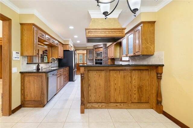 2629 Benton Dr, Brenham, TX 77833 - kitchen with appliances with stainless steel finishes, decorative backsplash, a peninsula, crown molding, and brown cabinetry