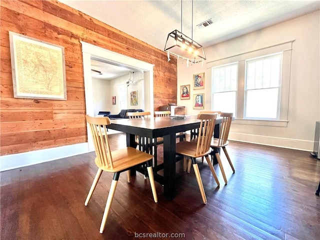 708 E 27th St E, Bryan, TX 77803 - dining area featuring a textured ceiling, a notable chandelier, dark wood-type flooring, and wooden walls