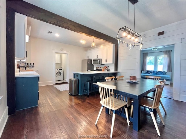 708 E 27th St E, Bryan, TX 77803 - dining space with wood walls, dark wood-type flooring, sink, beamed ceiling, and washer / clothes dryer