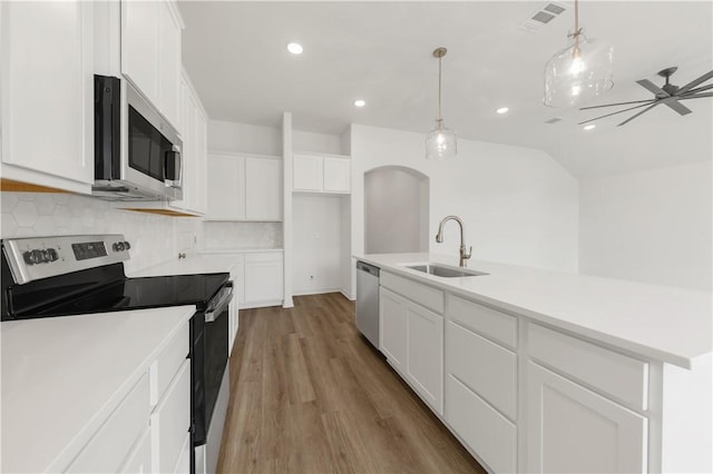 kitchen featuring sink, appliances with stainless steel finishes, white cabinetry, decorative backsplash, and decorative light fixtures