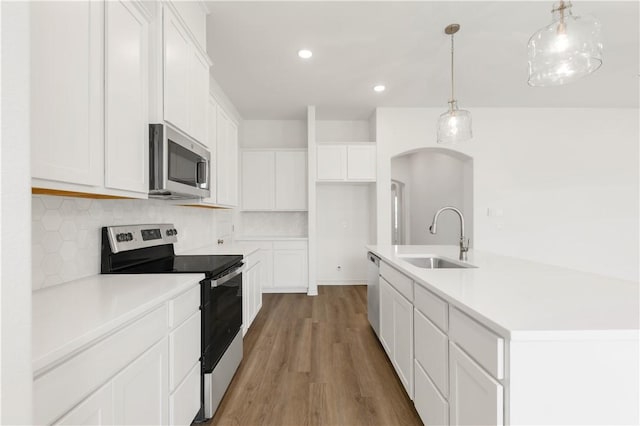 kitchen featuring stainless steel appliances, white cabinetry, and hanging light fixtures