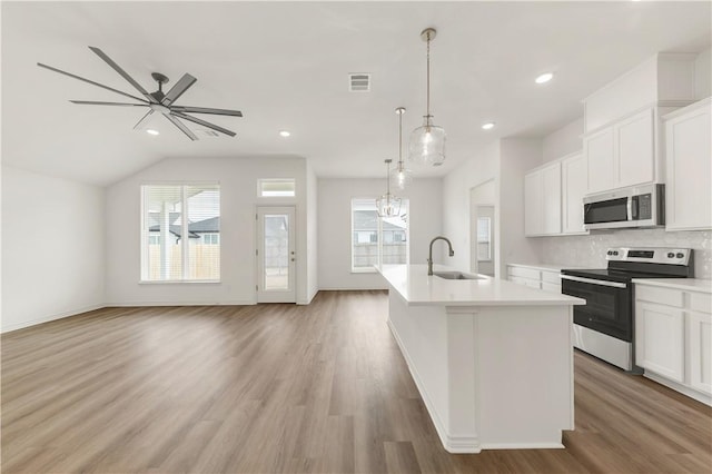 kitchen featuring sink, appliances with stainless steel finishes, hanging light fixtures, an island with sink, and white cabinets