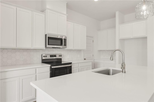 kitchen featuring white cabinetry, sink, hanging light fixtures, and appliances with stainless steel finishes