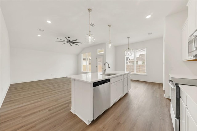 kitchen with an island with sink, white cabinetry, sink, hanging light fixtures, and stainless steel appliances