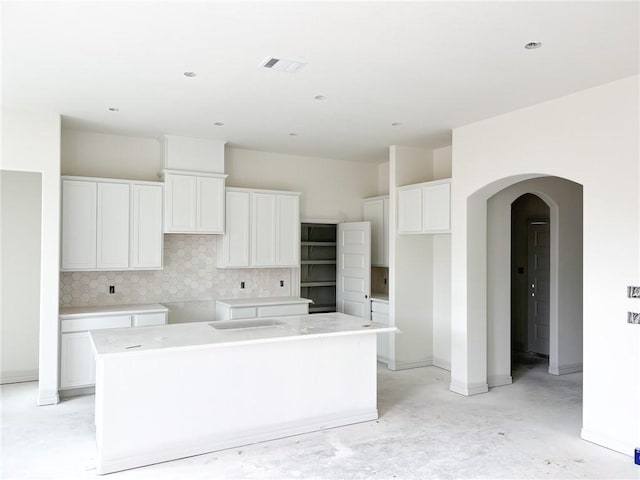 kitchen featuring decorative backsplash, a kitchen island, and white cabinetry