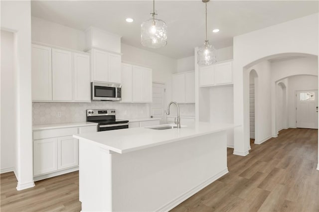 kitchen with stainless steel appliances, sink, a center island with sink, and white cabinets