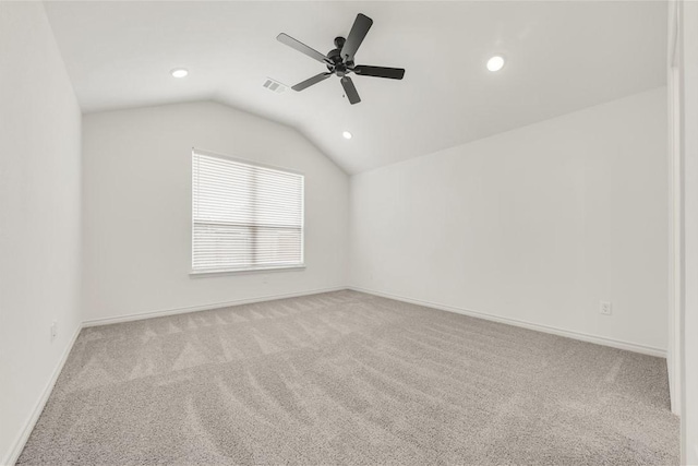 carpeted spare room featuring vaulted ceiling and ceiling fan