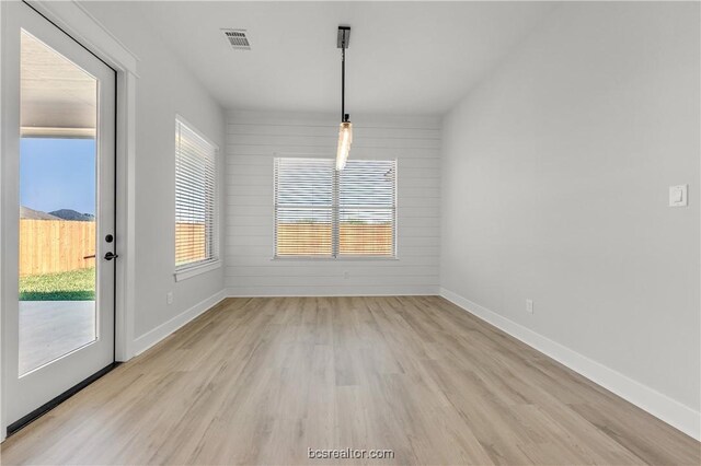 unfurnished dining area featuring wood walls and light wood-type flooring