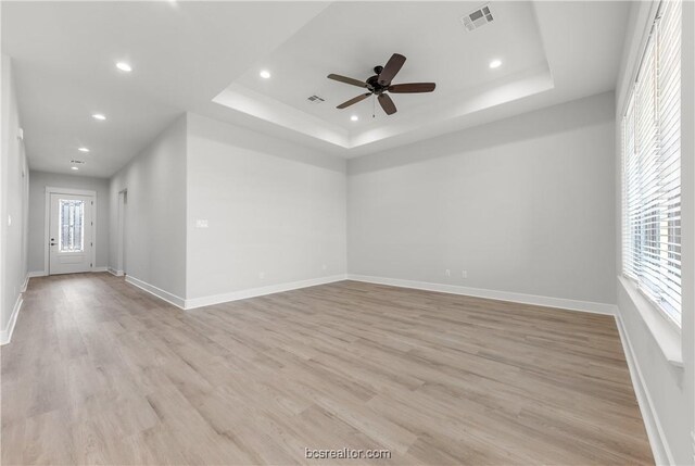 spare room with plenty of natural light, light hardwood / wood-style floors, and a tray ceiling