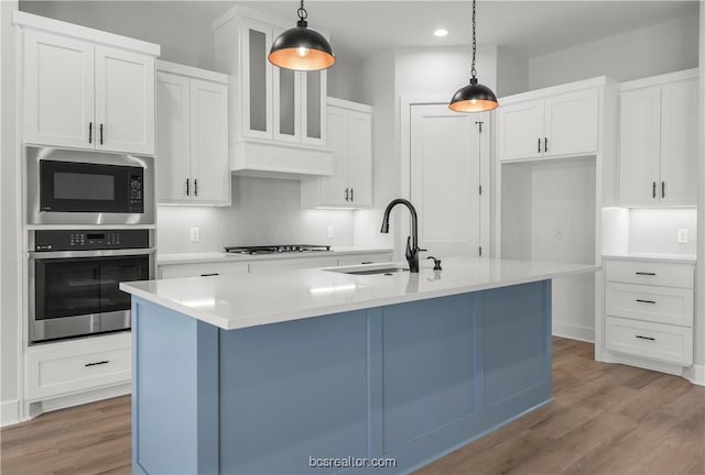 kitchen featuring pendant lighting, oven, sink, and a kitchen island with sink