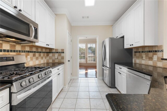 kitchen with backsplash, white cabinetry, stainless steel appliances, and light tile patterned floors