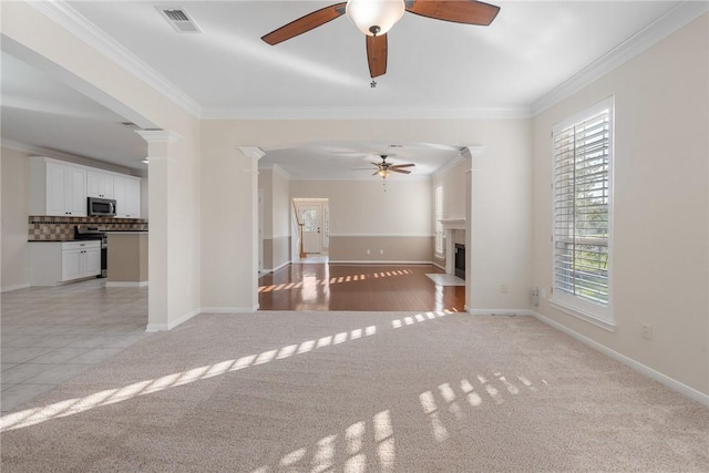 unfurnished living room with ceiling fan, ornamental molding, and light carpet