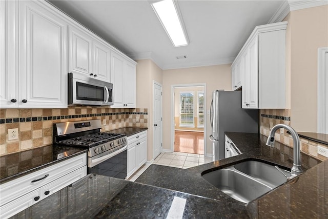 kitchen with backsplash, ornamental molding, stainless steel appliances, sink, and white cabinets