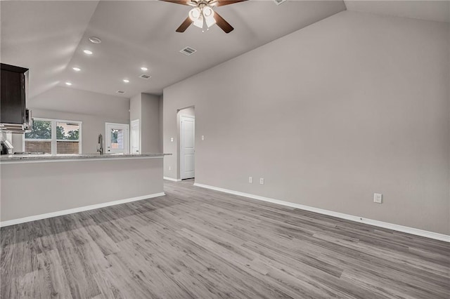 unfurnished living room with lofted ceiling, ceiling fan, light wood-type flooring, and sink