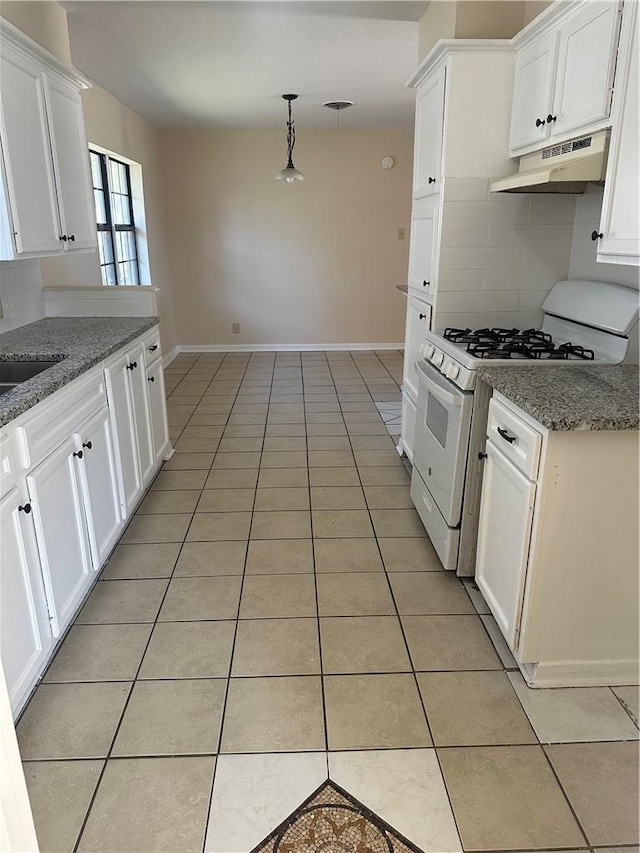 kitchen featuring light tile patterned flooring, stone countertops, pendant lighting, white cabinetry, and white gas range