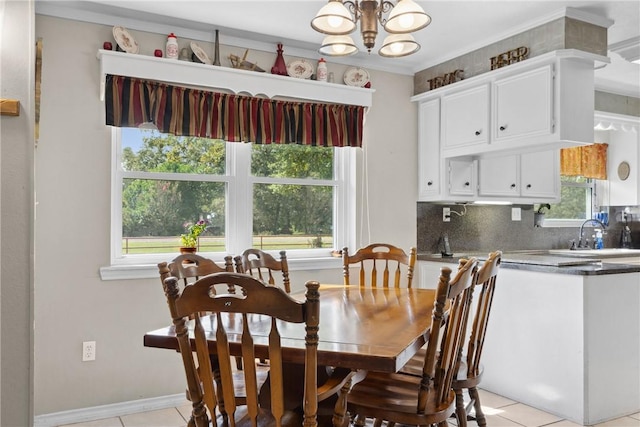 tiled dining space featuring a notable chandelier, plenty of natural light, crown molding, and sink