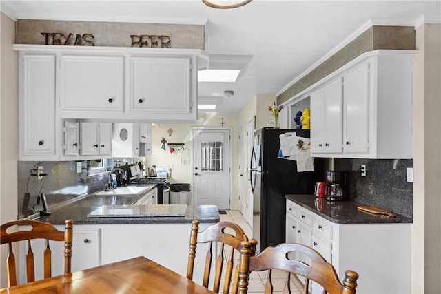 kitchen with tile patterned floors, sink, kitchen peninsula, tasteful backsplash, and white cabinetry