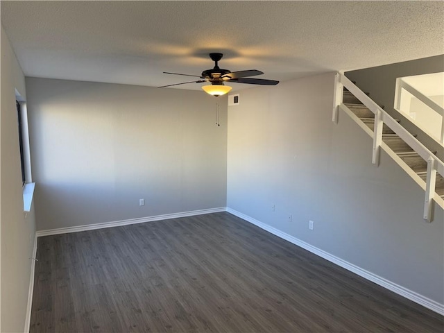 spare room with a textured ceiling, ceiling fan, and dark hardwood / wood-style floors