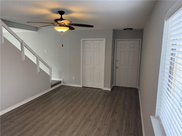 unfurnished living room featuring a wealth of natural light, dark hardwood / wood-style floors, and ceiling fan