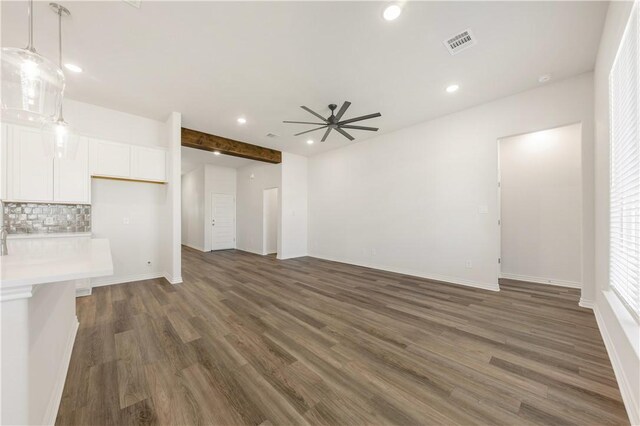 unfurnished living room featuring ceiling fan, beam ceiling, and dark wood-type flooring