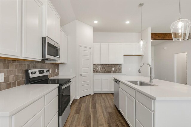 kitchen with white cabinets, appliances with stainless steel finishes, a kitchen island with sink, and sink