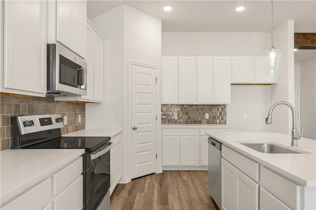 kitchen featuring white cabinets, stainless steel appliances, hanging light fixtures, and sink