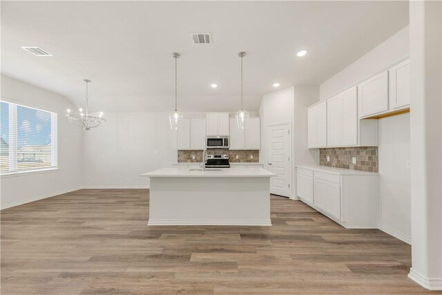 kitchen featuring stainless steel appliances, white cabinetry, and an island with sink