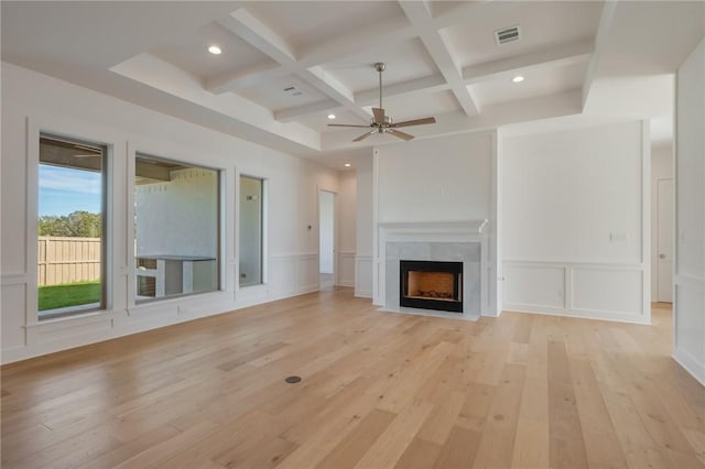 unfurnished living room with coffered ceiling, light hardwood / wood-style flooring, beamed ceiling, ceiling fan, and a premium fireplace