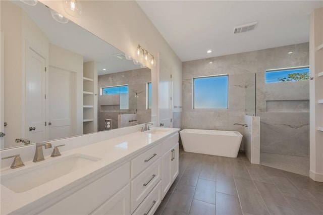 bathroom featuring tile patterned flooring, shower with separate bathtub, tile walls, and vanity