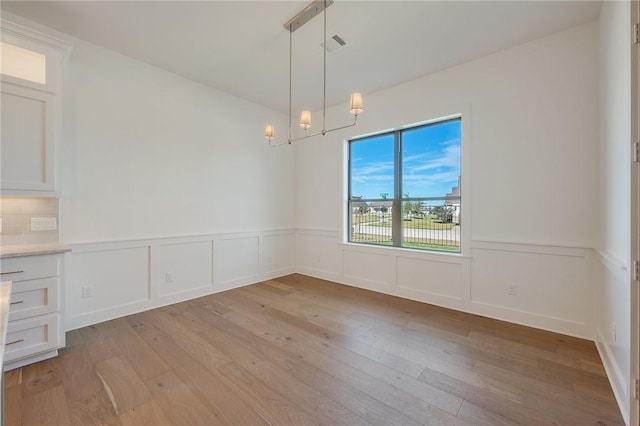 unfurnished dining area with a chandelier and light hardwood / wood-style flooring