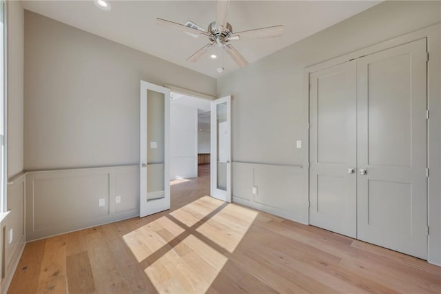 unfurnished bedroom featuring french doors, ceiling fan, light hardwood / wood-style floors, and a closet