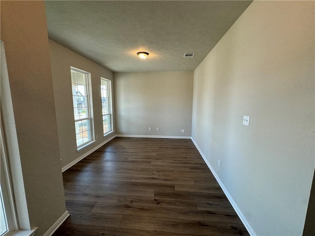 spare room featuring dark hardwood / wood-style floors and a textured ceiling