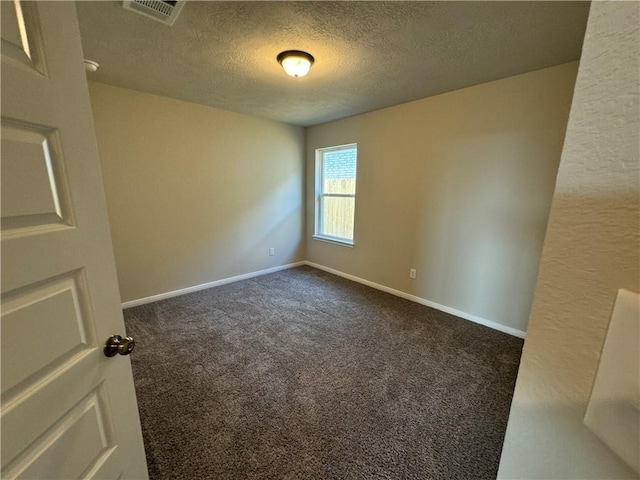 carpeted empty room featuring a textured ceiling