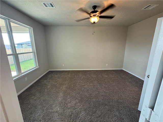 spare room featuring dark colored carpet, a textured ceiling, and ceiling fan