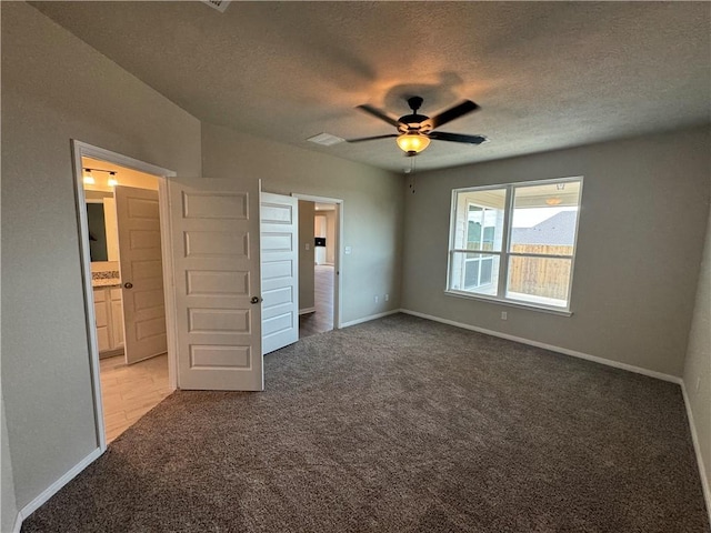 unfurnished bedroom with a textured ceiling, light colored carpet, ceiling fan, and ensuite bathroom