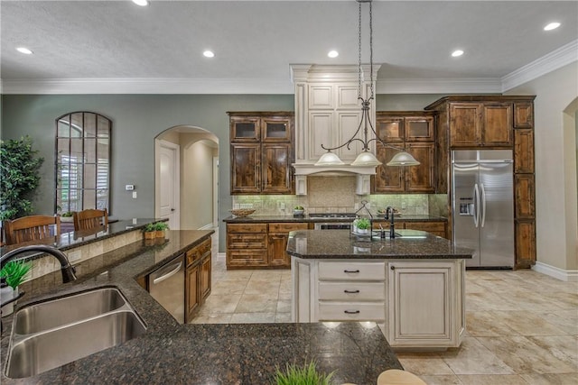 4920 Whistling Straits Loop, College Station, TX 77845 - kitchen featuring appliances with stainless steel finishes, arched walkways, a center island with sink, tasteful backsplash, and dark stone counters