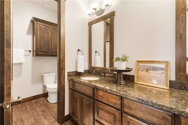 bathroom featuring baseboards, wood tiled floor, toilet, and vanity