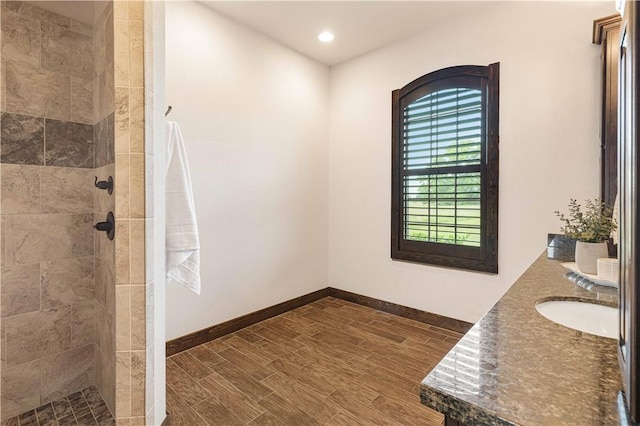 full bathroom featuring baseboards, recessed lighting, tiled shower, and a sink